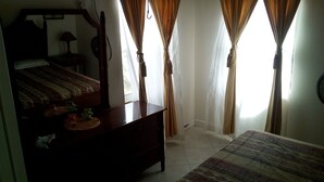 A room with a bed, a wooden dresser, a mirror, and curtains. - Winfort 4 Bay Walk (Gros Islet)