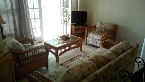 A living room with wicker furniture, a glass coffee table, and a television on a stand. - Winfort 4 Bay Walk (Gros Islet)