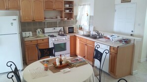 A compact kitchen with wooden cabinets, a gas stove, a microwave, and a sink. - Winfort 4 Bay Walk (Gros Islet)