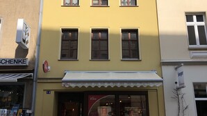 Een geel gebouw met een etalage, een ladder buiten en een bord met de tekst 'Seeger'.