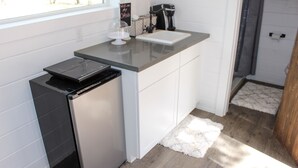 Een kleine keuken met een vaatwasser, een koffiezetapparaat en een wit aanrecht.