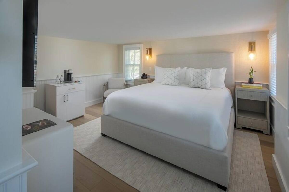 A modern bedroom with a large bed, bedside tables, a desk, and a window.