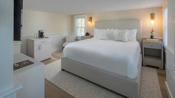 A modern bedroom with a large bed, bedside tables, a desk, and a window.