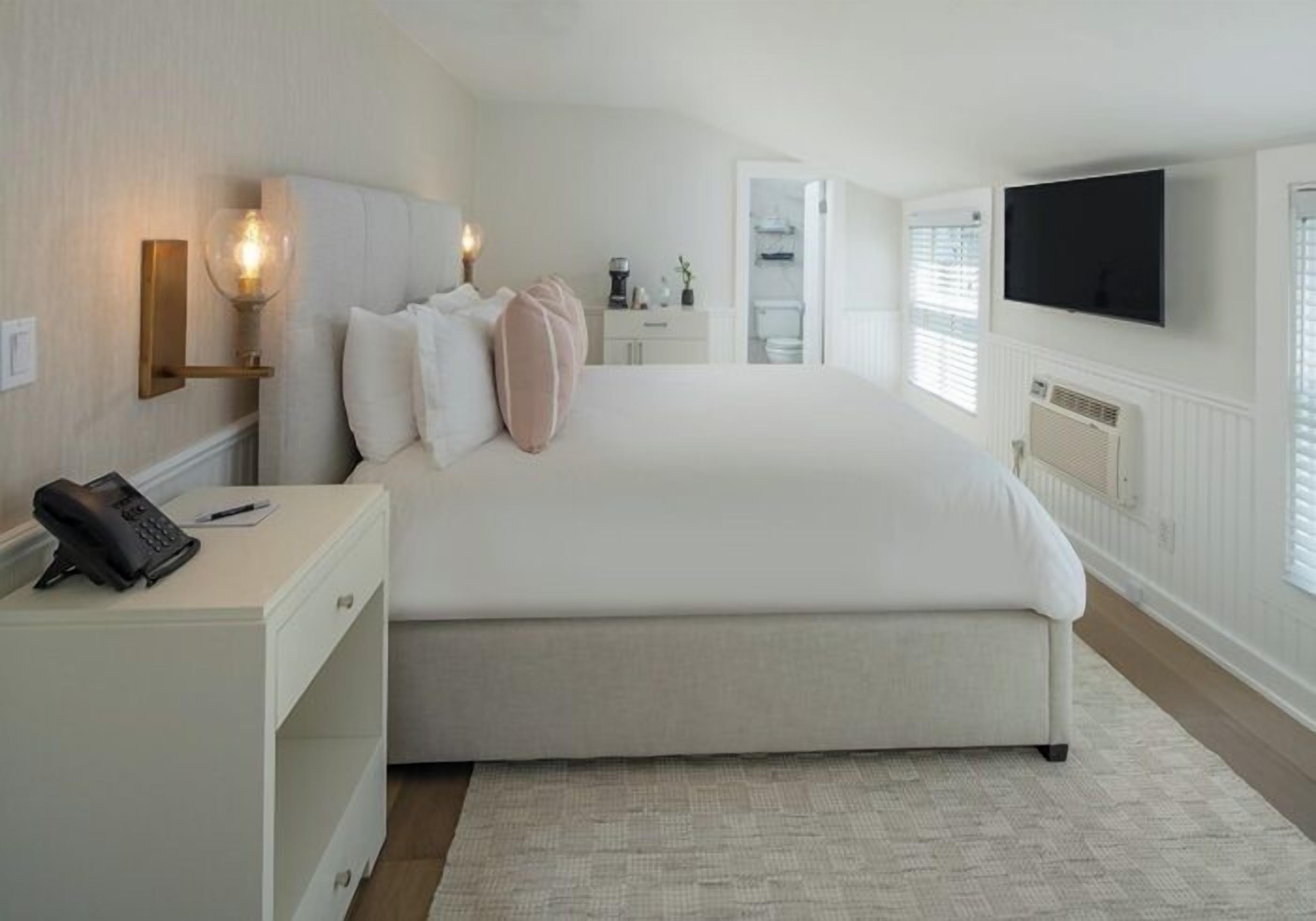 A bedroom with a large bed, bedside tables, a flat-screen TV, and a telephone.