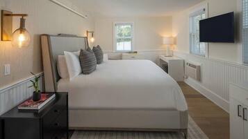 Une chambre avec un grand lit, des tables de chevet, une télévision et une fenêtre avec des stores.