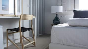 Una habitación de hotel con cama, una silla, una lámpara y una ventana con cortinas.
