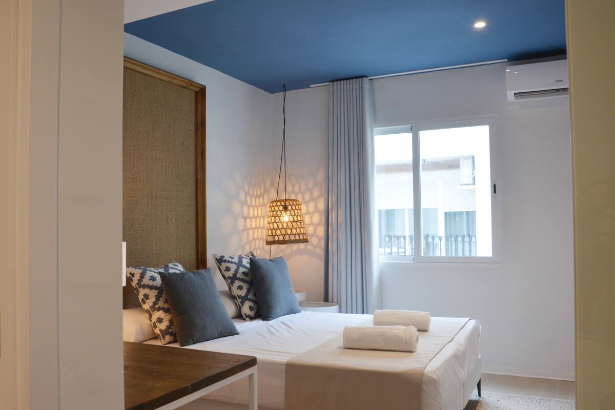 Une chambre à coucher avec un lit, une table de chevet et une fenêtre avec des rideaux.