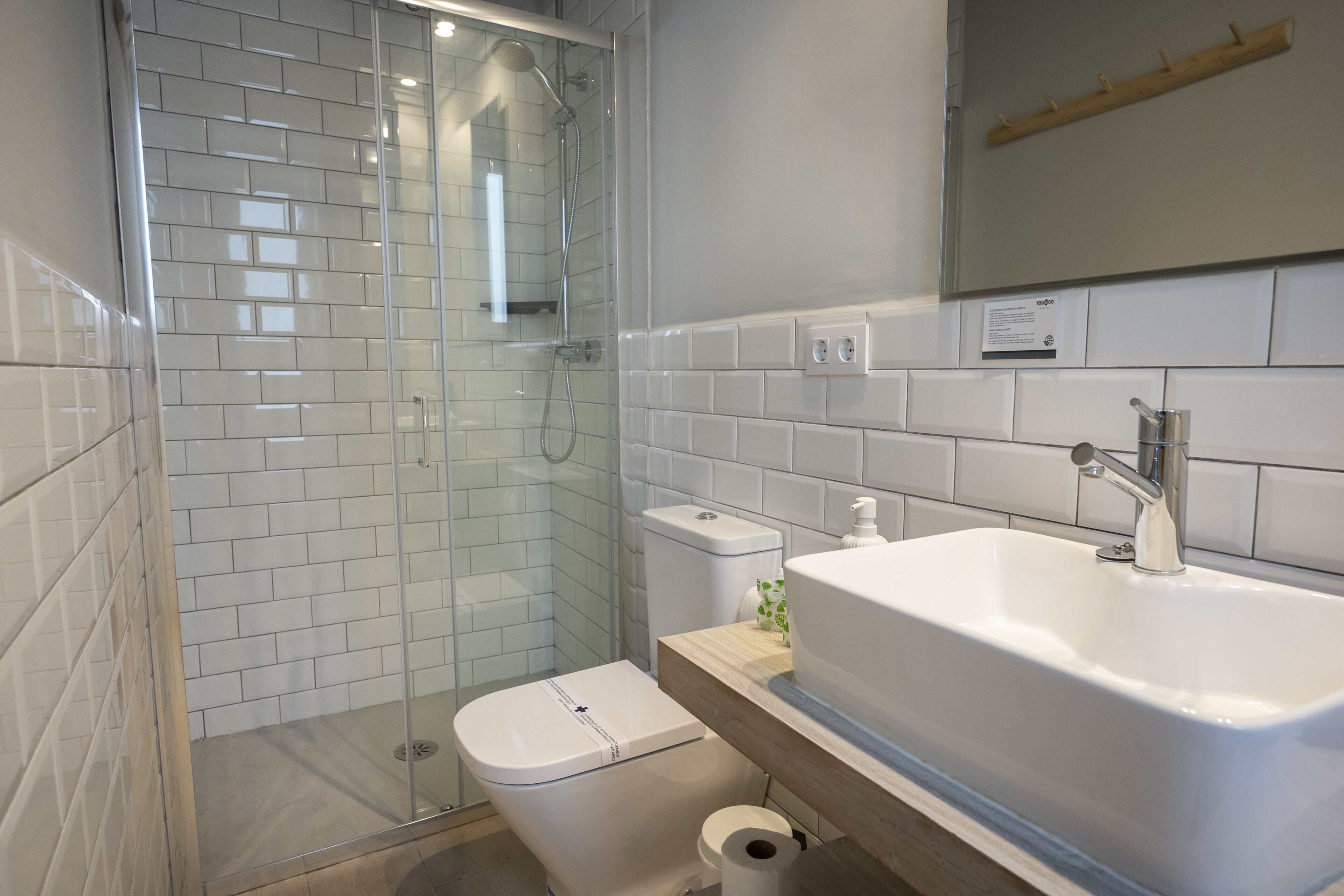 A modern bathroom with a glass-enclosed shower, a white sink, and a toilet.