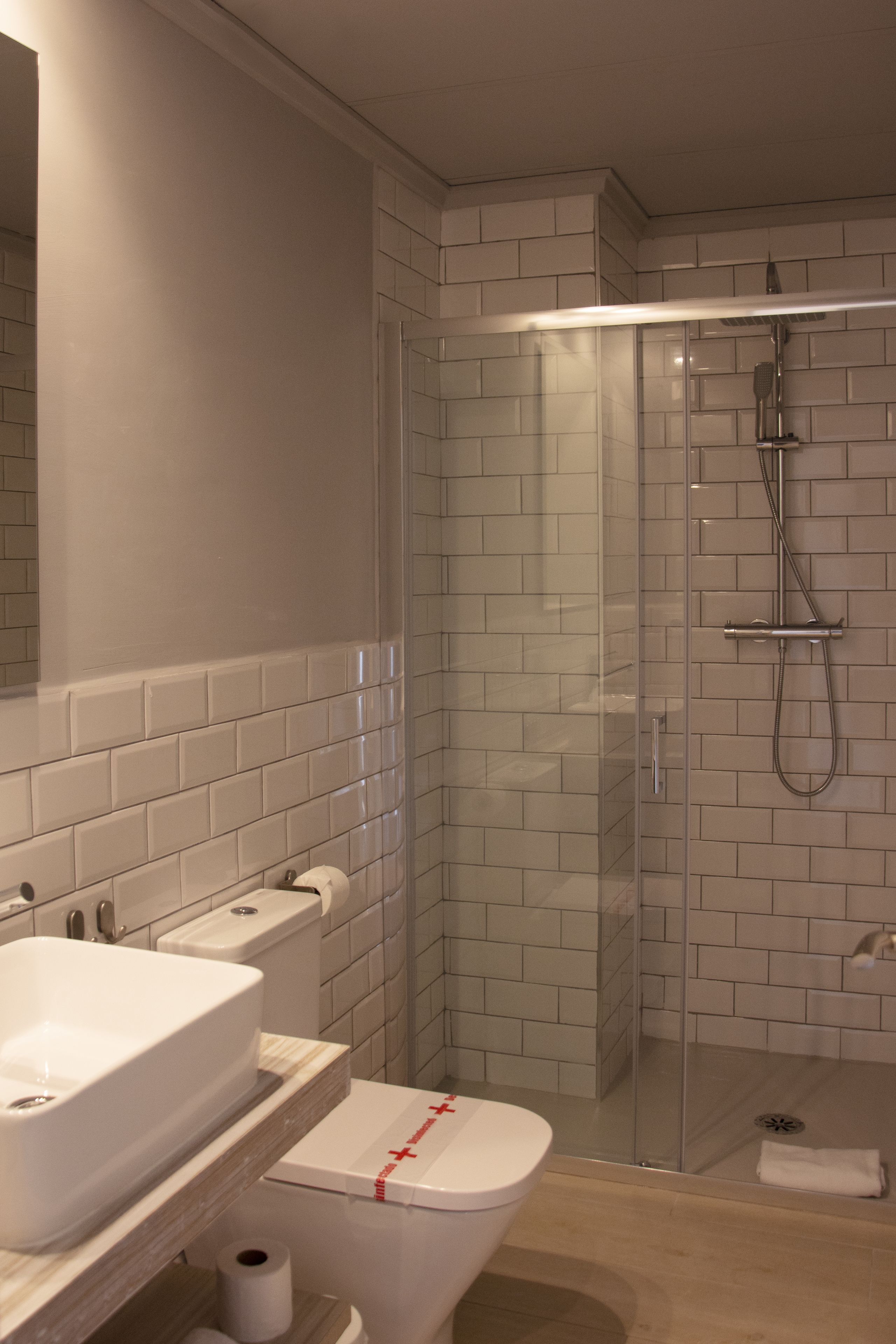 A modern bathroom with a glass-enclosed shower, a white sink, and a toilet.