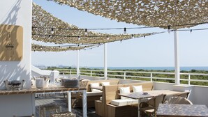 Eine Terrasse mit Sitzgelegenheiten im Freien, einer Bar und Blick aufs Meer.