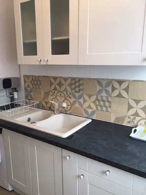 A kitchen with a double sink, white cabinets, a black countertop, and patterned backsplash tiles. - "CHEZ VIORIKA" Apartment: 3 Bedrooms, 4 Beds, Parking (Rouen)