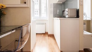 Una cocina compacta con microondas, un radiador y una ventana que proporciona luz natural.
