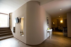 Un interior moderno con una pared curva, una escalera, un televisor de pantalla plana y un comedor con una mesa y sillas.