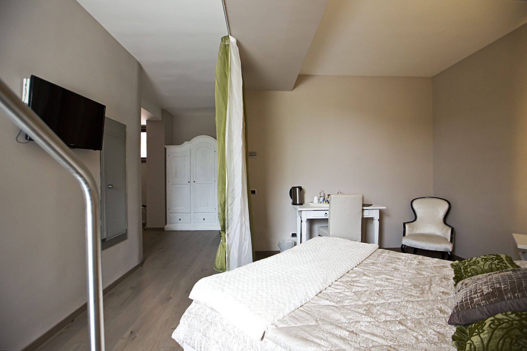 A bedroom with a bed, a desk, a chair, a television, and a staircase.