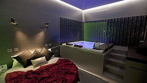 A modern hotel room with a large bed, a separate bathroom with a bathtub, and a staircase leading to an upper level. - Hotel Tiro a Volo (Pozzuoli)