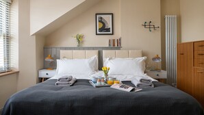 A neatly arranged bedroom with a large bed, two bedside tables with lamps, a radiator, and a wooden wardrobe. - A beautiful and cosy dog friendly cottage with flexible sleeping arrangements (Greenlaw)