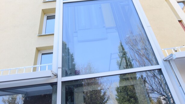 A multi-story building with a glass facade and balconies.