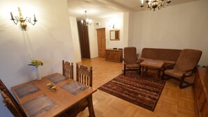 A dining area with a wooden table and chairs, a rug, and a sofa.