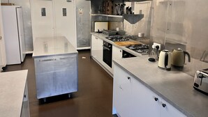 Una cocina moderna con electrodomésticos de acero inoxidable, una tabla de cortar de madera y una cafetera.