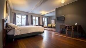 A bedroom with a large bed, a desk, and a chair, a television, and a window with curtains. - B&B Kwaadham 52 - Music Hotel Ghent (Ghent)