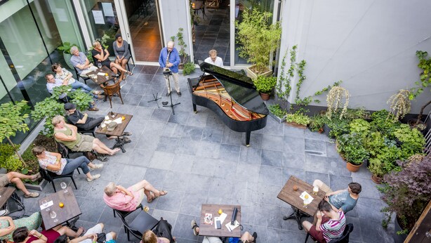 An outdoor patio area with a grand piano, seating arrangements, and potted plants. - B&B Kwaadham 52 - Music Hotel Ghent (Ghent)