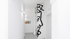 Un pasillo con una gran obra de arte abstracto negra en la pared y una obra colorida en la pared opuesta.