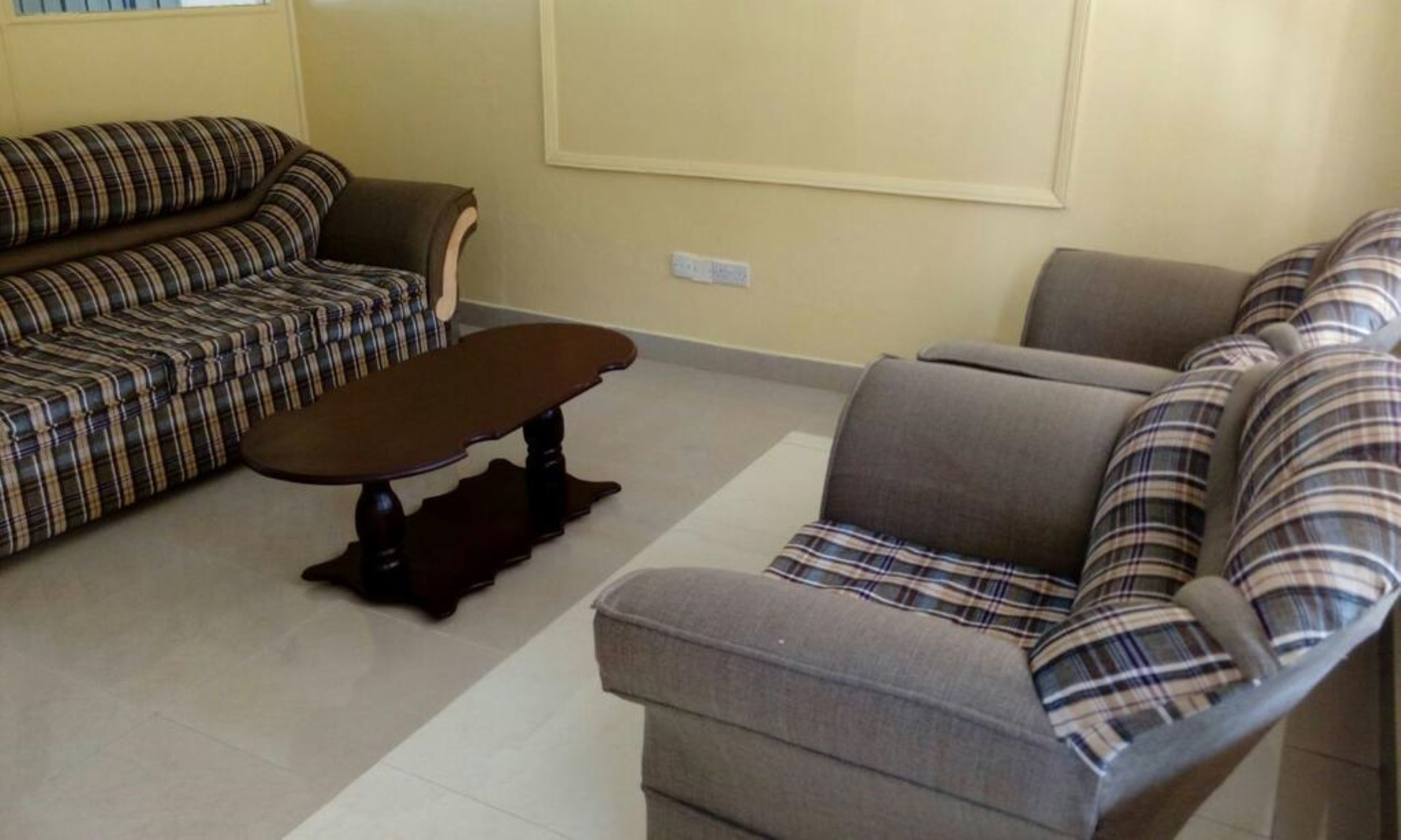 A living room with a sofa set, a coffee table, and a wall-mounted TV.