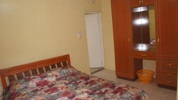 Una camera da letto con un letto, un armadio in legno e un piccolo cesto arancione.