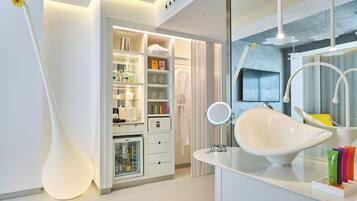 A modern bathroom with a large white basin, a mirror, and a storage cabinet.