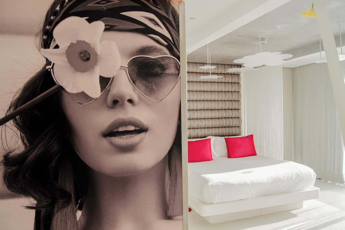 A modern bedroom with a large bed, white bedding, and red pillows.