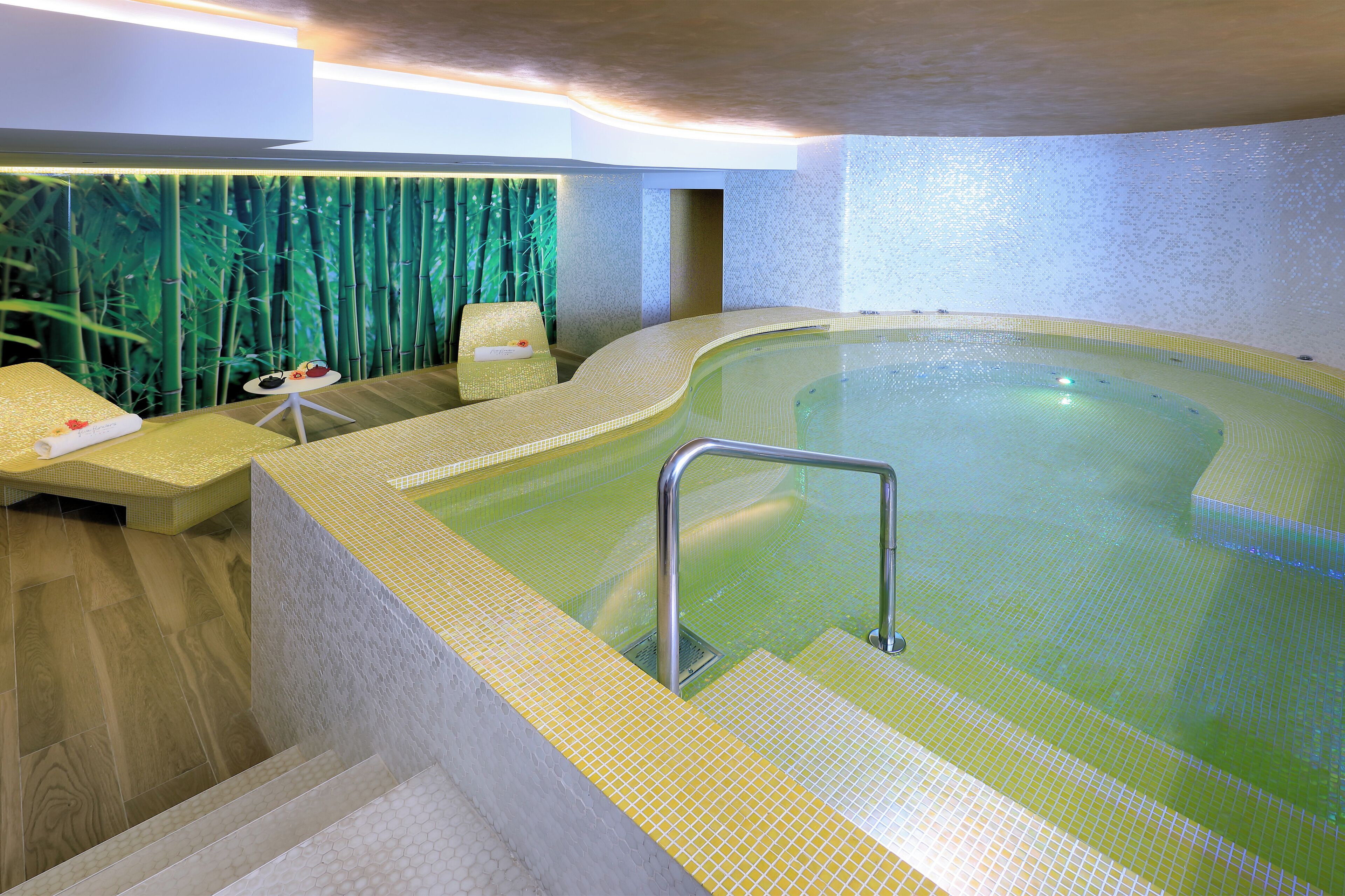 Ein Wellnessbereich mit Whirlpool, Sitzgelegenheiten und einer Wand im Bambus-Design.