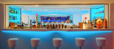 A bar area with a counter, bar stools, and shelves stocked with bottles and glasses.