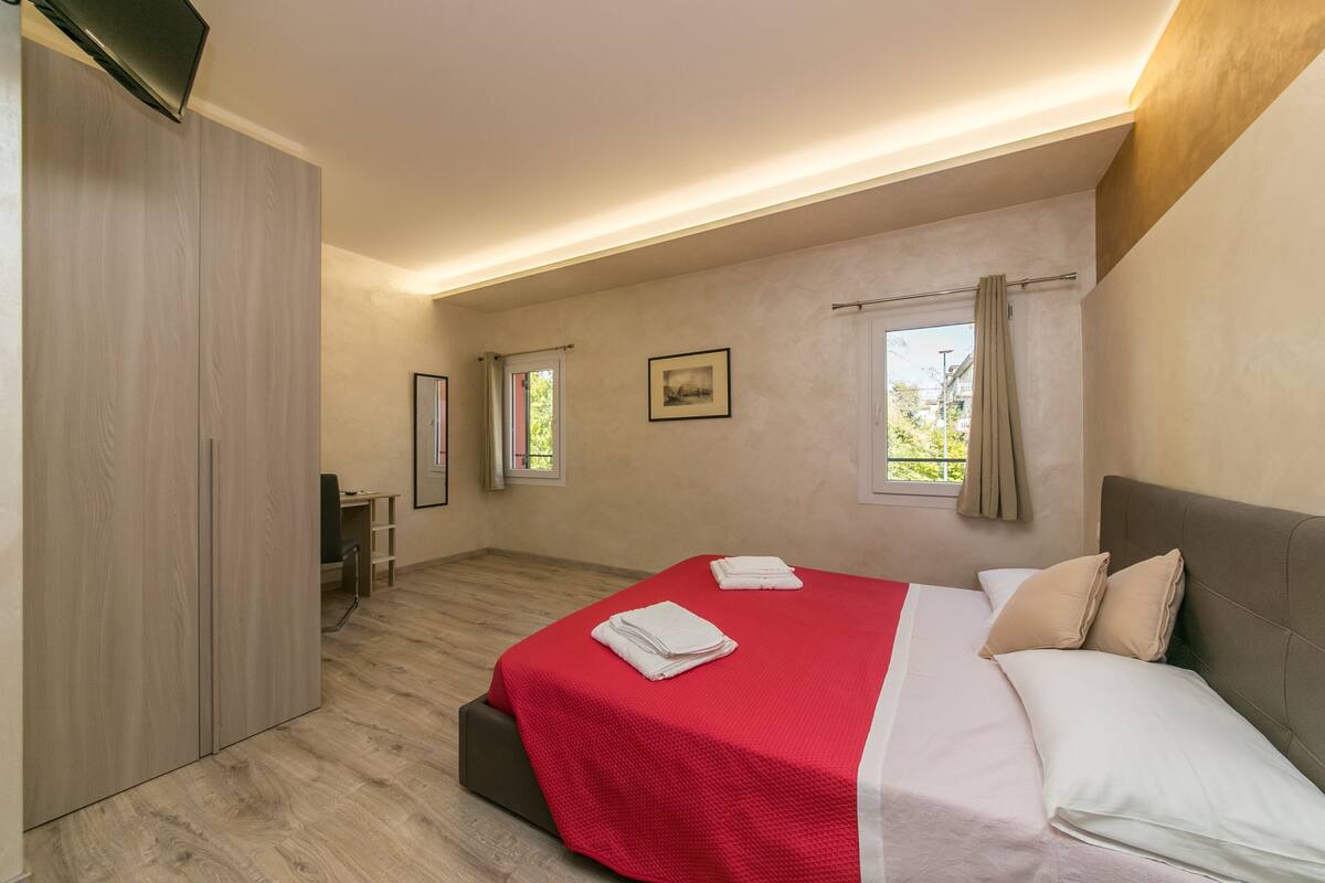 A bedroom with a bed, a desk, and a wardrobe.