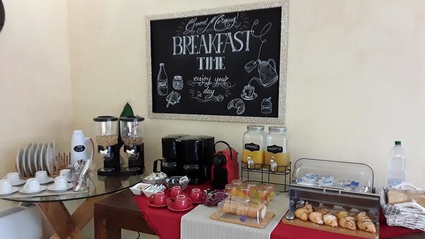 A breakfast setup with a chalkboard sign, coffee makers, mugs, and pastries. - Red Lion Guest House (Mestre)