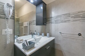 A modern bathroom with a large mirror, a hairdryer, and a towel rack. - Red Lion Guest House (Mestre)