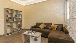 A living room with a brown leather sofa, a wooden coffee table, and a bookshelf filled with books. - Red Lion Guest House (Mestre)