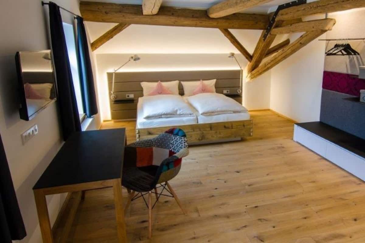 A compact bedroom with a bed, a small desk, and a chair.