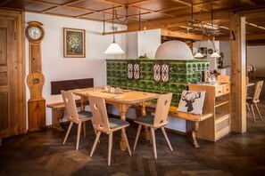 A wooden dining area with a round table and chairs, a clock, and a green tiled backsplash. - Zum Hirschen -  hotel & gasthaus beim stöckeler (Scheidegg)