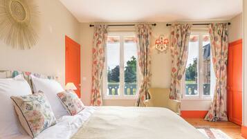 A bedroom with a bed, curtains, a chair, and a view of the outside.