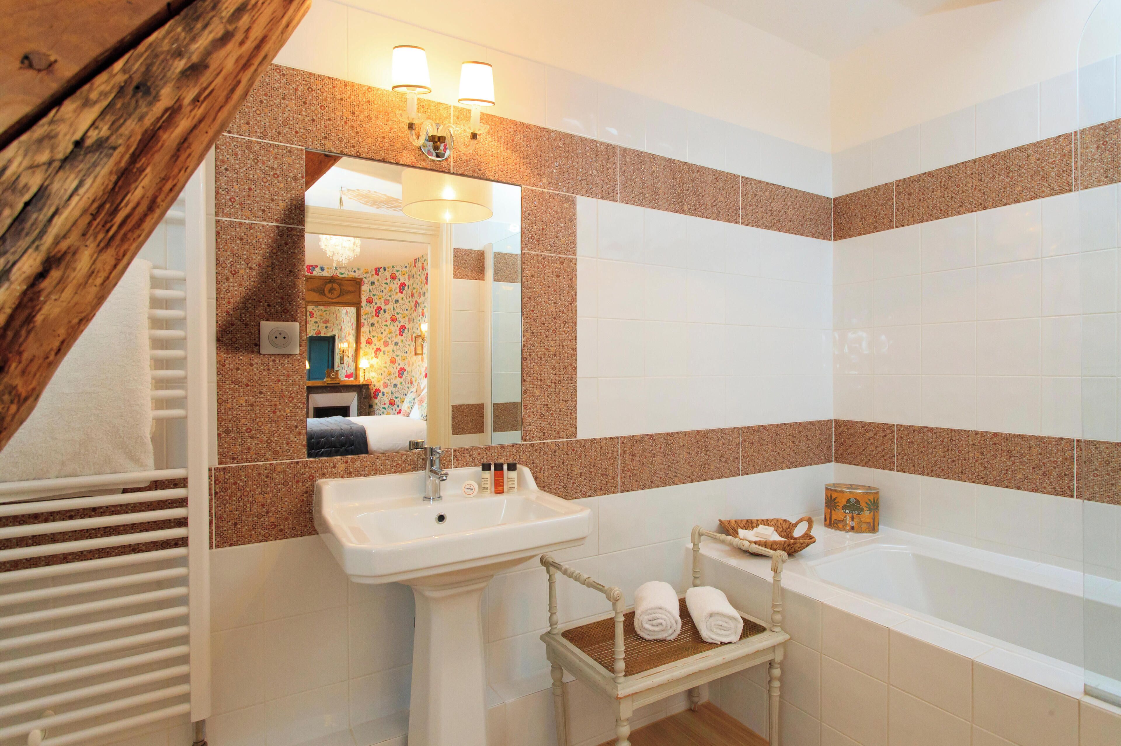 A bathroom with a sink, mirror, and bathtub.