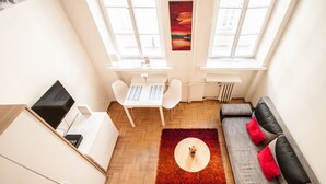A compact living space with a kitchenette, a dining area, and a sofa with red cushions. - Elegant Apartment Royal Castle (Warsaw)