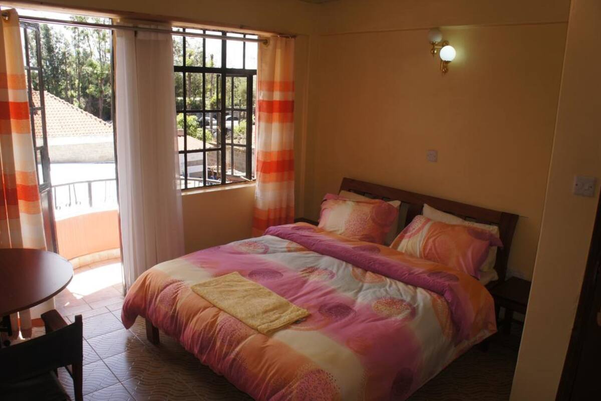 Une chambre à coucher avec un lit, une table et une fenêtre avec des rideaux.
