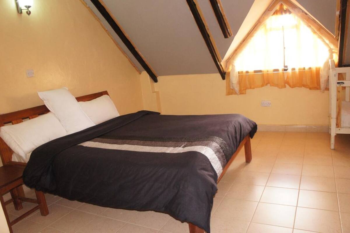 Une chambre à coucher avec un lit, une tête de lit en bois et une fenêtre avec des rideaux.