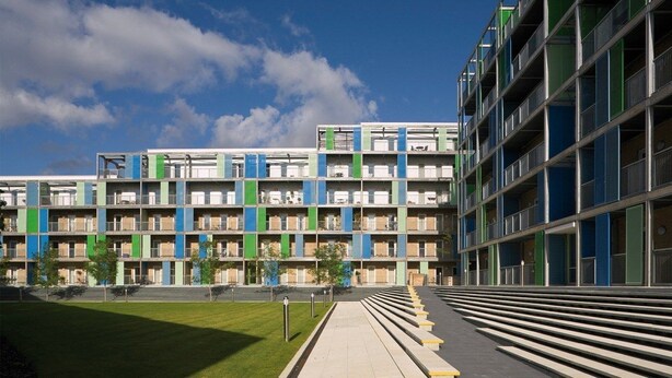 En byggnad med flera våningar och en modern arkitektonisk design, med en rad balkonger och en central innergård.