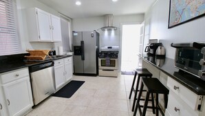A modern kitchen with white cabinets, stainless steel appliances, and a black countertop.