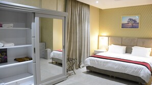 Habitación de hotel con cama, armario, espejo, mesita de noche y un cuadro colgado en la pared.