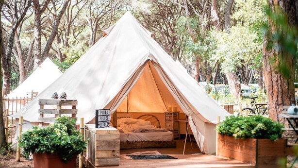 A cozy tent with a bed, a small table, and a sign. - Pigna Felice - Glamping (Grosseto)