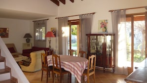 A dining area with a table set for four, wooden chairs, a red lamp, and a cabinet with glass doors.