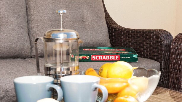 Un rincón acogedor con cafetera, un juego de Scrabble y un frutero.