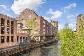 A canal-side building with multiple windows, a staircase, and a bridge over the water.